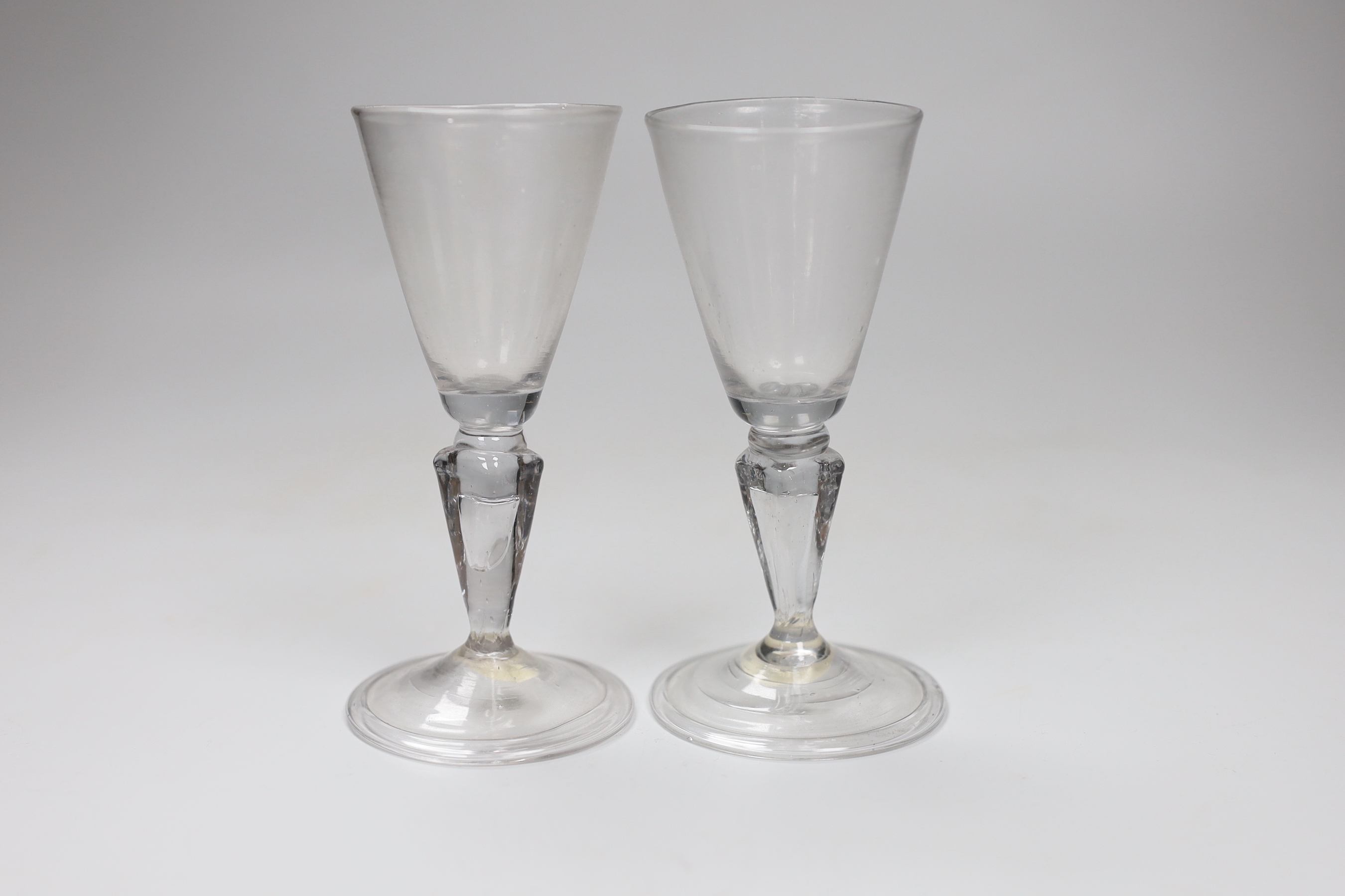 A pair of Continental facon de Venice wine glasses, first half 18th century, round funnel bowls and hollow moulded pedestal stems, folded feet, tallest 13.5cm